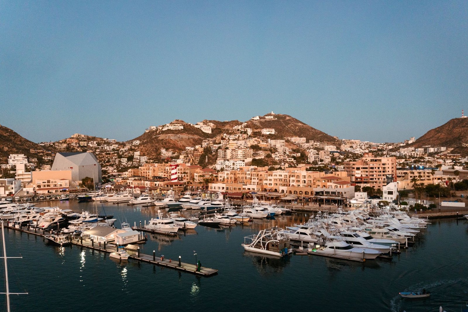Cabo San Lucas marina with yachts and hillside homes at sunrise