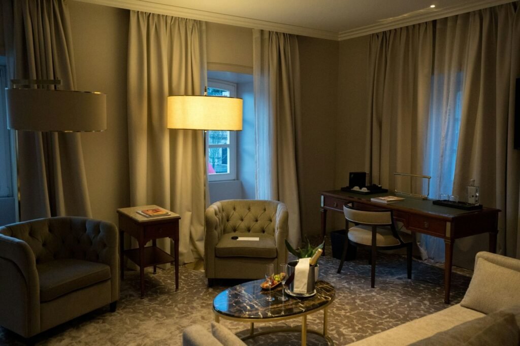 A warm, well-lit hotel room with seating and a desk.